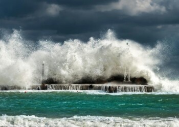 Dramatic ocean waves crashing against a concrete structure in Pantanassa, capturing nature's raw power.
